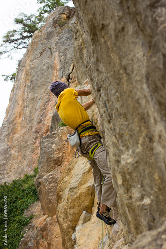 Young male climber hanging on a cliff with a rope.