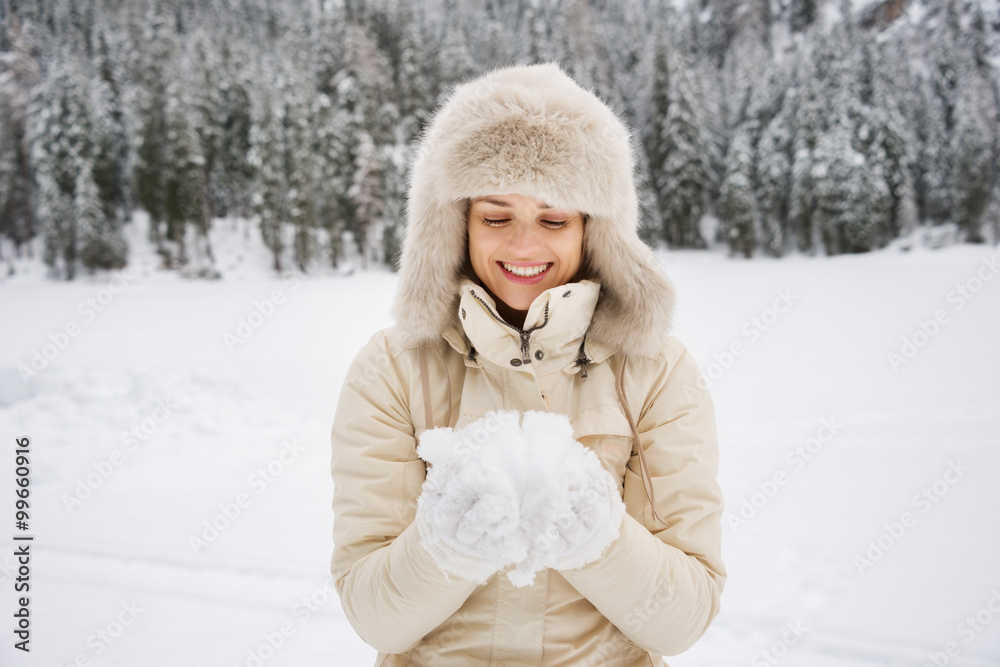 Woman looking on snow in hands while standing outdoors Woman looking on snow in hands while standing outdoors