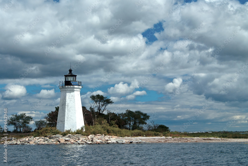 Sun shines through clouds illuminating weathered Black Rock Harbor lighthouse tower in Bridgeport, Connecticut.