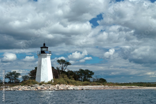 Sun shines through clouds illuminating weathered Black Rock Harbor lighthouse tower in Bridgeport, Connecticut.