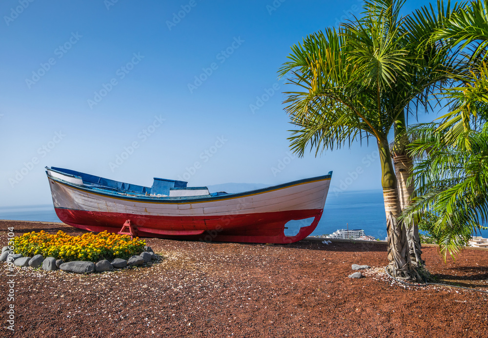 A colourful painted fishing boat on display near the ocean in Los Gigantes, Tenerife, Canary Islands,