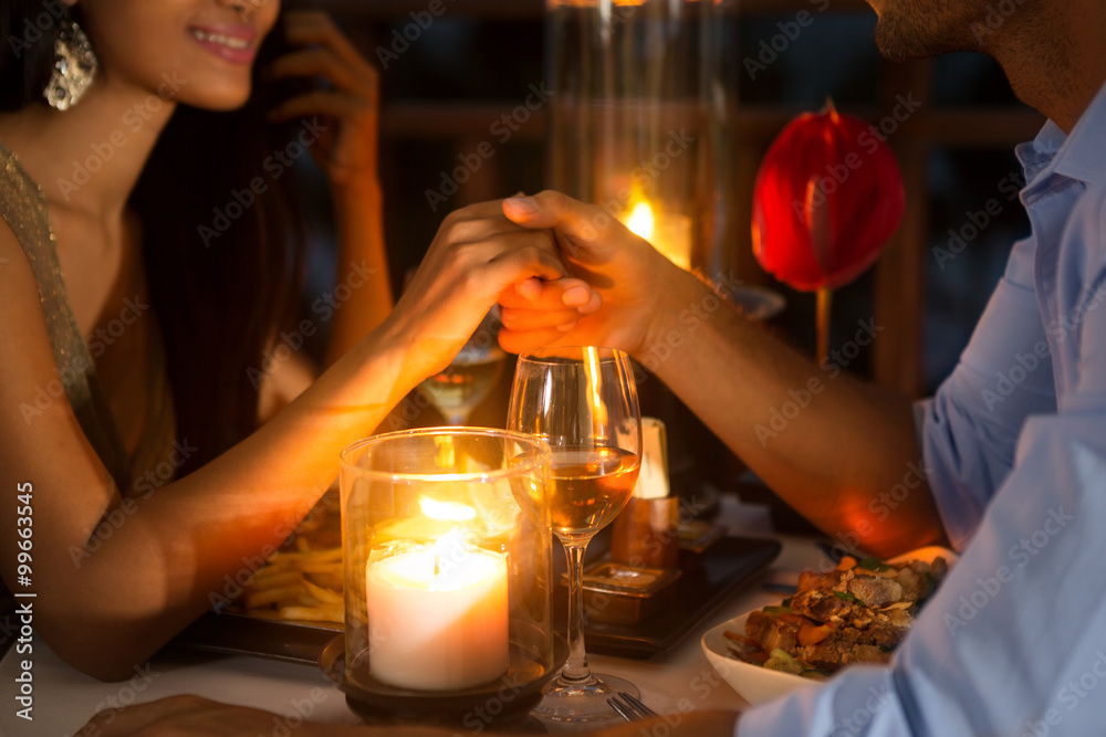 Romantic couple holding hands together over candlelight - obrazy, fototapety, plakaty 