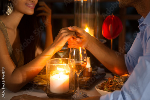 Obraz na plátně Romantic couple holding hands together over candlelight