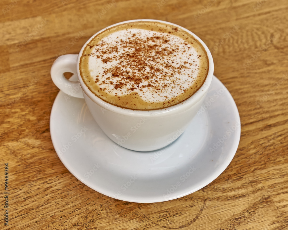 Cappuccino in white cup close-up on wood background Cappuccino in white cup close-up on wood background