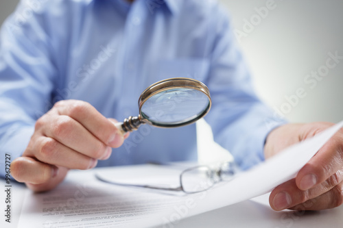 Businessman with magnifying glass reading documents