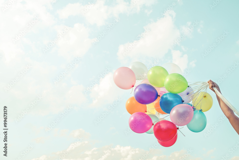 Girl hand holding multicolored balloons done with a retro vintage instagram filter effect, concept of happy birthday in summer and wedding honeymoon party (Vintage color tone) - obrazy, fototapety, plakaty 