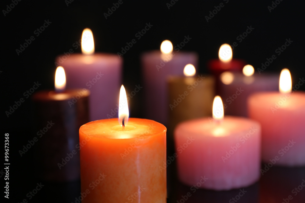 Many burning small candles on dark background, close-up