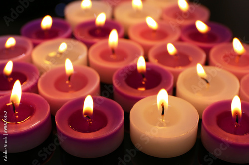 Many burning small candles on dark background, close-up