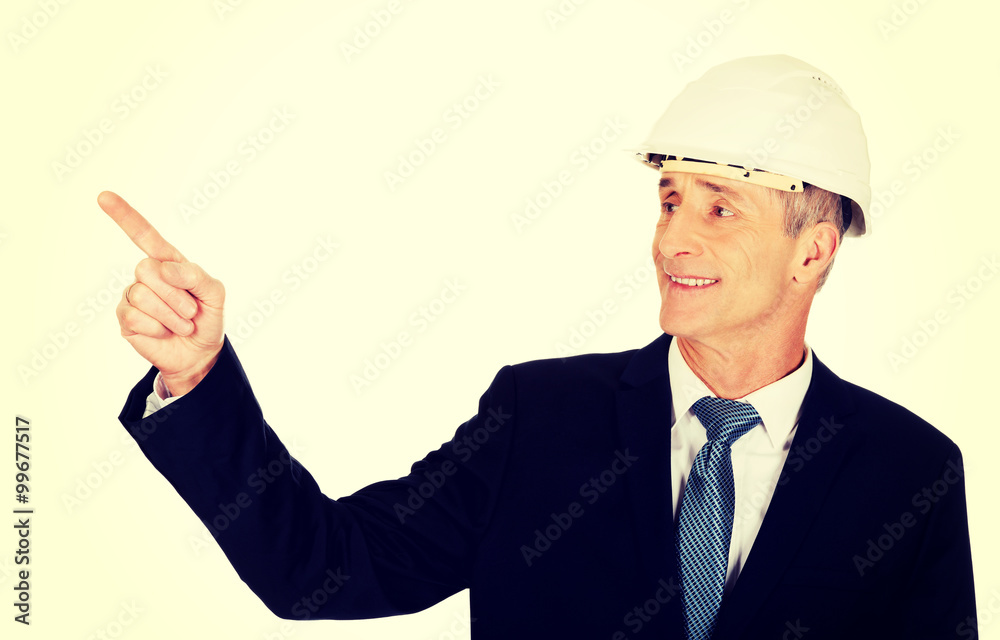 Smiling businessman with hard hat pointing up Smiling businessman with hard hat pointing up
