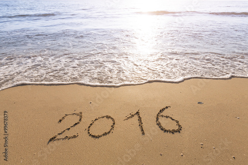 2016 written on a sandy beach with bright sun