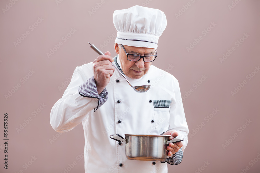 Portrait of restaurant's chef in working uniform tasting the meal Portrait of restaurant's chef in working uniform tasting the meal