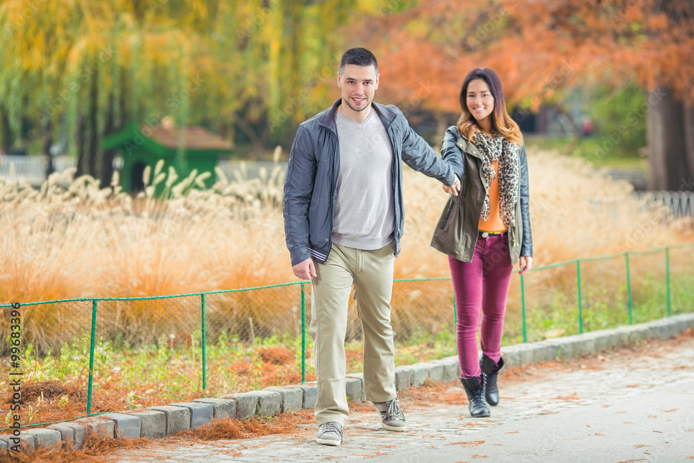 Happy young couple having fun walking through the colorful park Happy young couple having fun walking through the colorful park