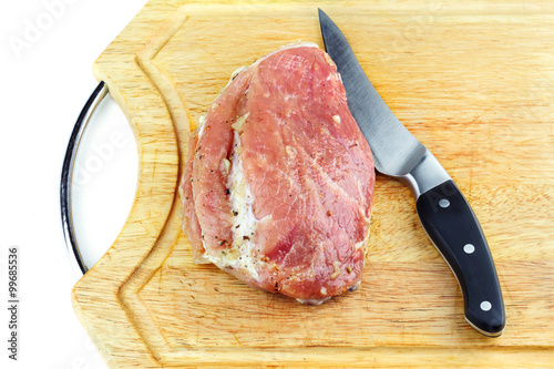 Raw meat with spices before cooking and knife on wood cutting board photo