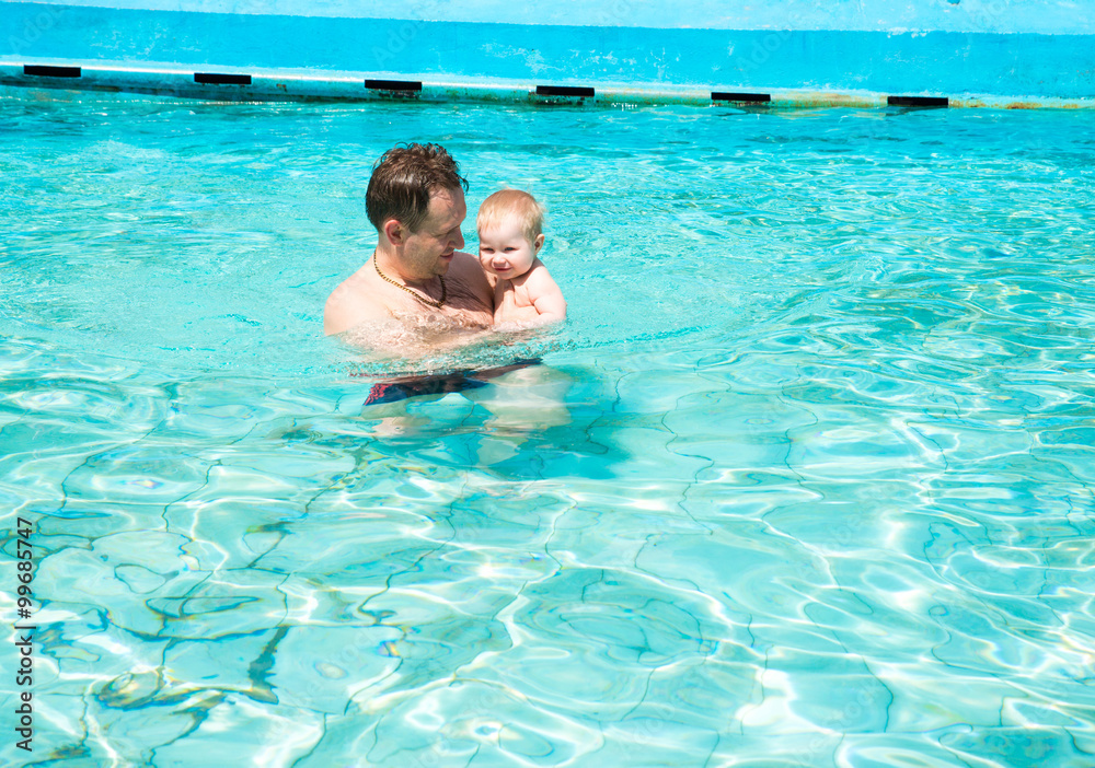 Active father teaching his child to swim in pool on tropical resort. Summer vacations and sport concept