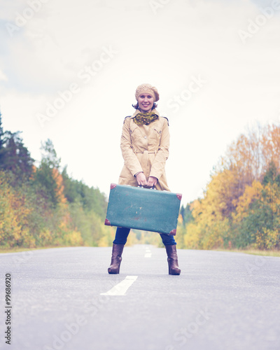 Elegant woman with a suitcase traveling the highway.