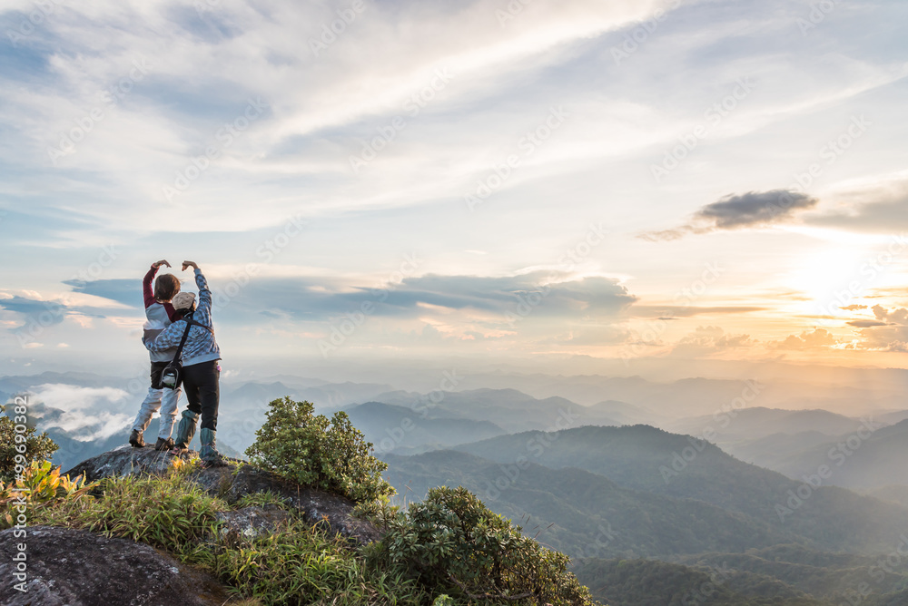 Young happy tourist on top of a mountain enjoying valley view