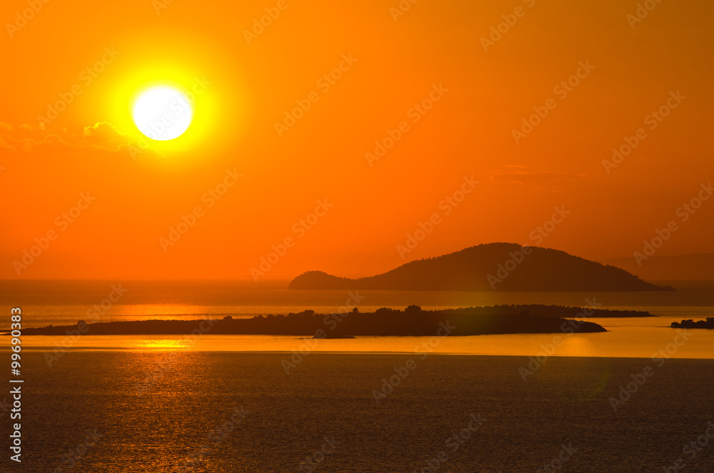 Sunset at sea, with small greek islands in background Sunset at sea, with small greek islands in background