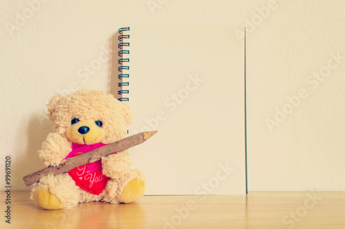 Φωτογραφία Teddy bear with pen and blank notebook