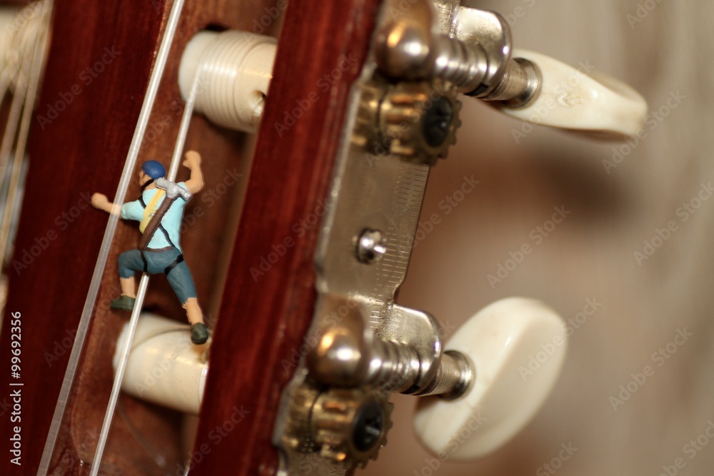 miniature di alpinisti mentre scalano una chitarra classica