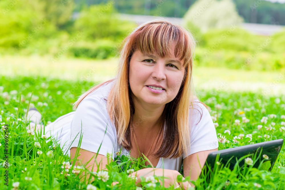 Woman in green grass with flowers horizontal picture Woman in green grass with flowers horizontal picture