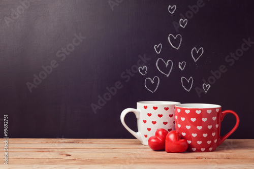 Valentine's day concept with hearts and cups over chalkboard background