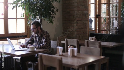 Young man drinking coffee on the street while using tablet computer

