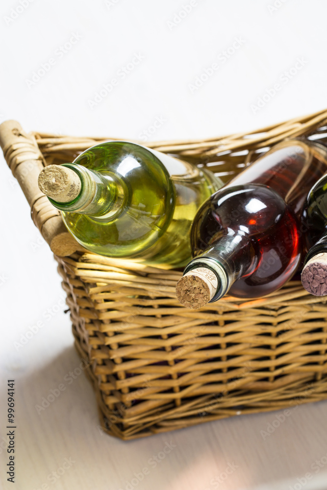 Obraz premium three bottles of white, rose and red whine in wicker basket