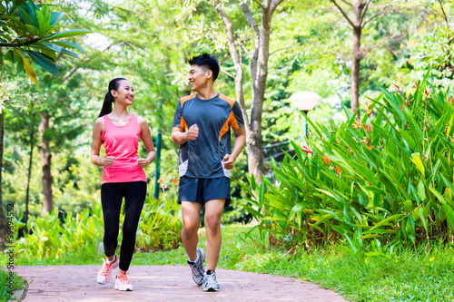 Fototapeta Naklejka Na Ścianę i Meble -  Asian Chinese man and woman jogging in city park
