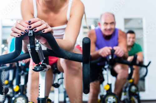 Fotografie Senior people in gym spinning on fitness bike