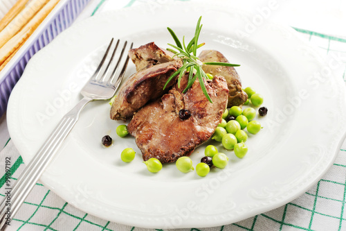 fried chicken livers with snow peas and rosemary on a white plat