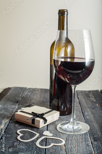 glass of red wine and a gift on a wooden background