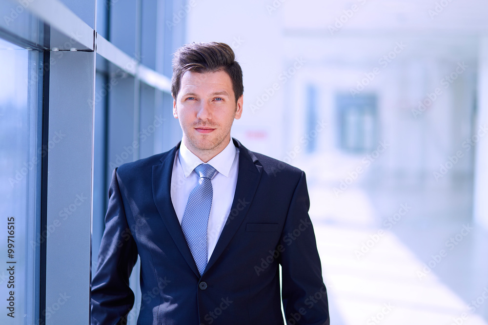 Portrait of businessman standing near window in office Portrait of businessman standing near window in office