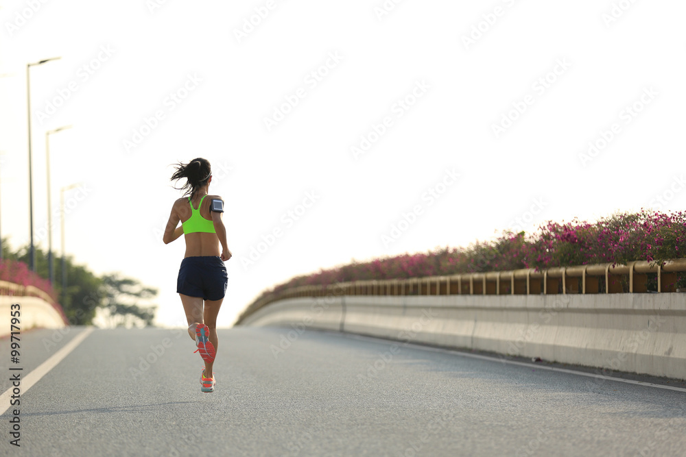 young woman runner running on city bridge road young woman runner running on city bridge road
