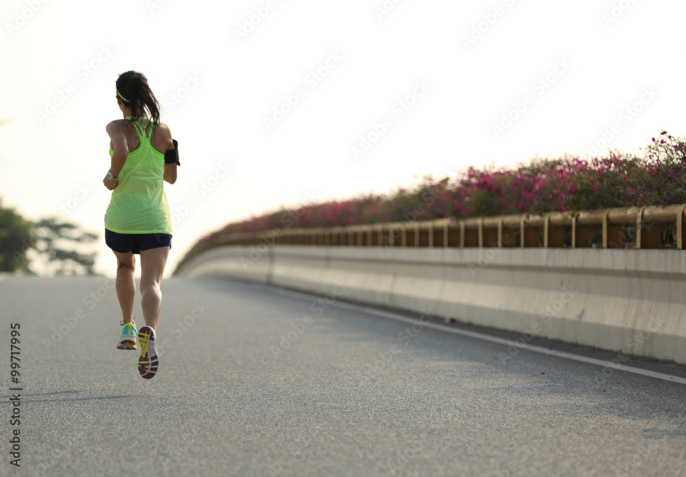young woman runner running on city bridge road young woman runner running on city bridge road