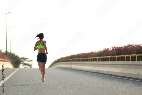 young woman runner running on city bridge road © lzf