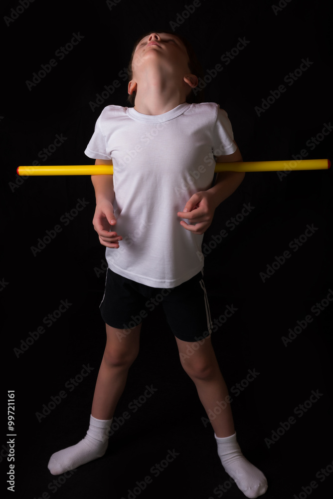 Boy athlete performs exercises with gymnastic stick in the gym Boy athlete performs exercises with gymnastic stick in the gym