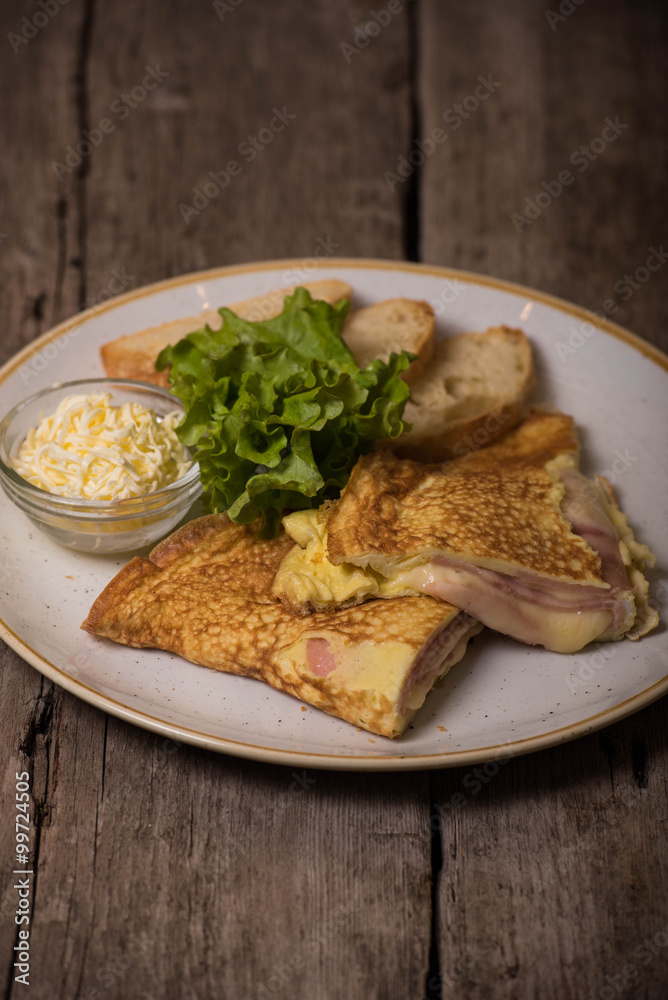 An omelet with ham and melted cheese, slices of white bread, grated butter on a plate An omelet with ham and melted cheese, slices of white bread, grated butter on a plate