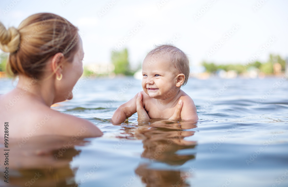 Young woman and little son playing in water on summer day Young woman and little son playing in water on summer day