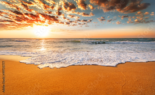 Fototapeta Naklejka Na Ścianę i Meble -  Colorful ocean beach sunrise with deep blue sky and sun rays.