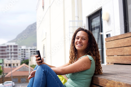 Young woman smiling with mobile phone in the city