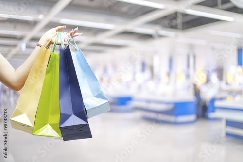 Hand holding shopping bags with blurred of cashier store backgro