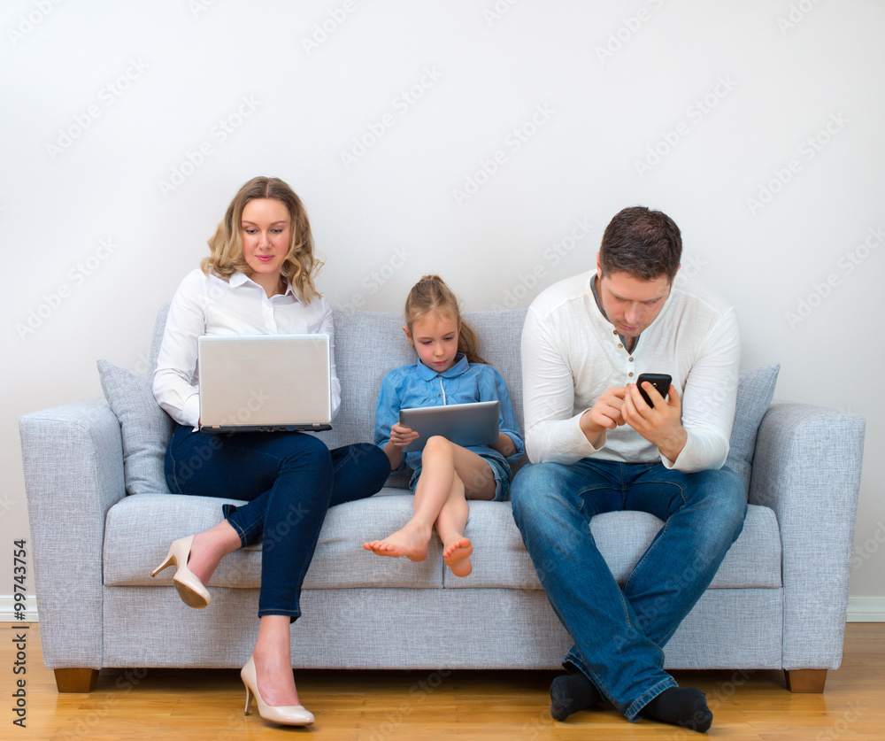 Modern family values. Father, mother and daughter using electronic devices.