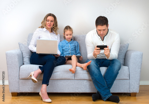 Modern family values. Father, mother and daughter using electronic devices.