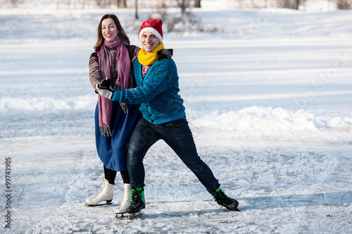Happy couple having fun ice skating on rink outdoors.