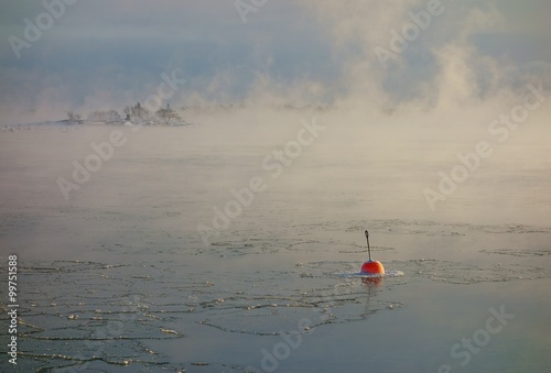 Bright red buoy floating alone in the freezing Baltic Sea in Helsinki, Finland just hours before complete freeze over of the sea on an extremely cold January morning (-20C) on 6 January 2016. 