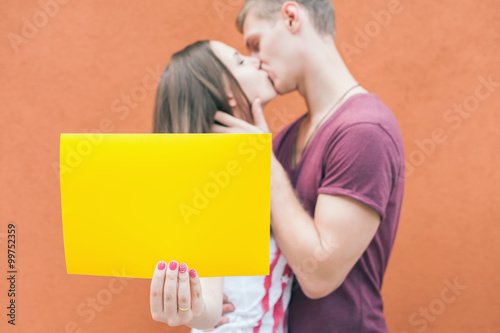 Happy couple kissing and holding frame at red background