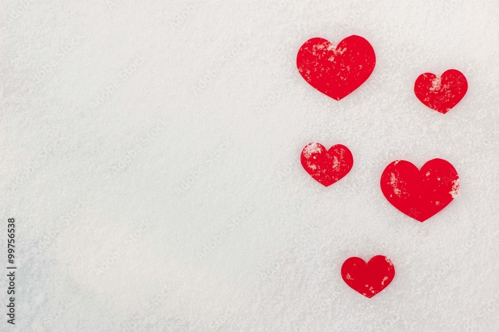 Red paper hearts on the snow.