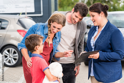 Autohändler berät Familie beim Autokauf und zeigt die Preisliste