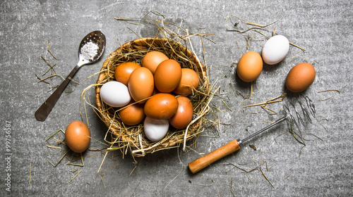 Basket with eggs, with a whisk . On stone background.