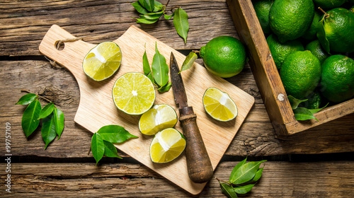 Sliced limes on a board with knife and box full .